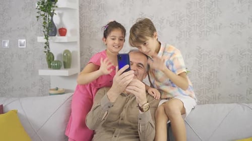 Grandfather and Grandchildren Video Chatting on Smartphone