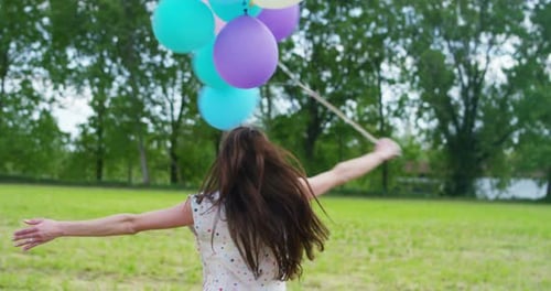 Joyful Woman Spins with Colorful Balloons in Meadow