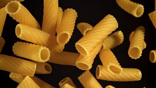 Rigatoni pasta falling in slow motion on black background