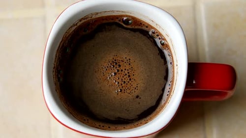 Rote Tasse Kaffee mit appetitlichem Schaum. Ansicht von oben