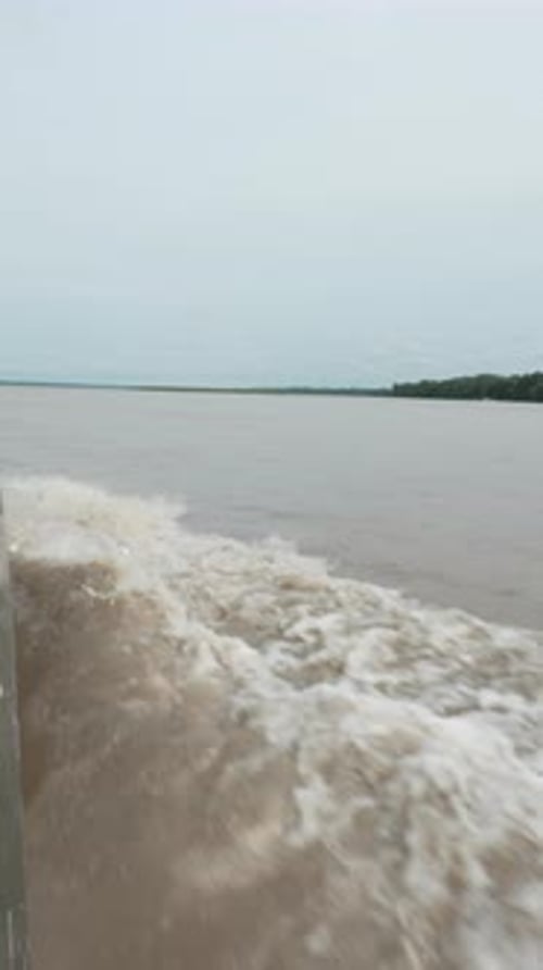 Waves from a Boat on the Amazon River Under Overcast Skies