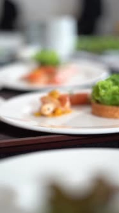 Chief plating breakfast with toast and greens blurred in the background, close up shot