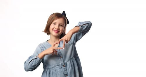 Smiling Little Girl Make Heart Sign with Hands in Casual Denim Dress Isolated on White Background
