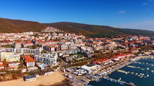 Numerous multi-storied hotels with red roofs built on the slope of the rocky shore.
