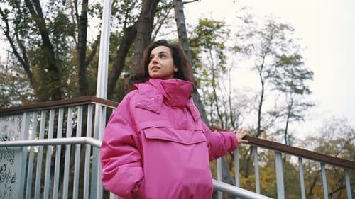 Pretty Young Woman Going Down Stairs While Walking in the Park Holding on to the Railing Wearing