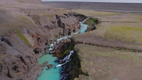 Aerial View of Icelandic Canyon with Blue River and Distant Structure