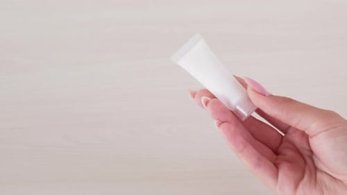 Hand Holding White Beauty Tube in Close Up