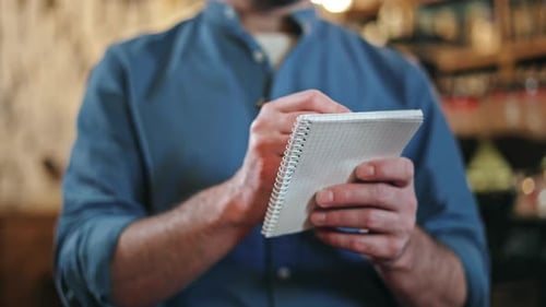 Close Up of Male Waiter Using Pen and Notepad for Taking Order at Restaurant