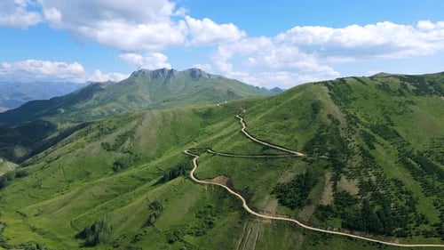 Lush Green Mountain Range with Winding Road Aerial