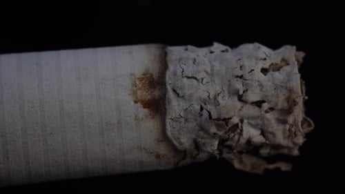Macro shot of burning cigarette on black background, no smoking campaign, health risks