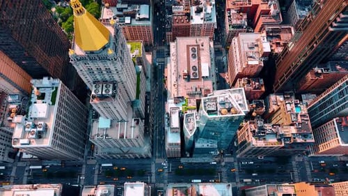Flying above the tops of diverse buildings in the modern cityscape of New York.