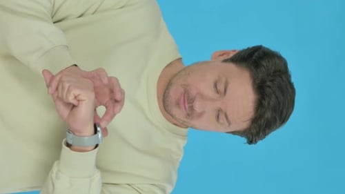 Junger Mann benutzt Smartwatch auf blauem Hintergrund, vertikales Video