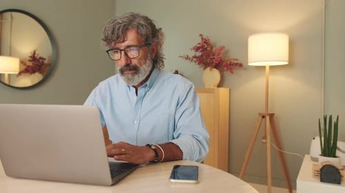 Mature Man Typing at Laptop in Home