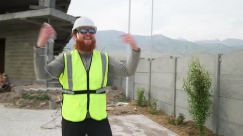 Empreiteiro engenheiro feliz dançando no canteiro de obras de bom humor, trabalhador barbudo louco