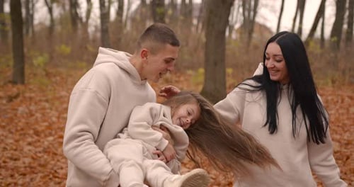 Parents with Daughter Playing in the Golden Autumn Forest