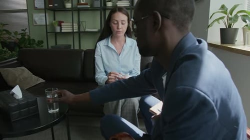 Male Counsellor Giving Glass of Water to Client, She Drinking