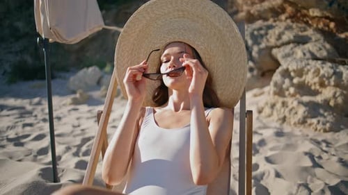 Carefree Lady prenant un bain de soleil sur la plage d'été, gros plan, femme élégante au chapeau de paille