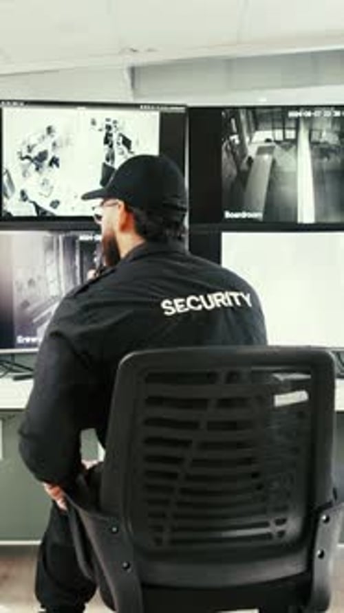 Security Guard Monitoring Surveillance Cameras in Control Room