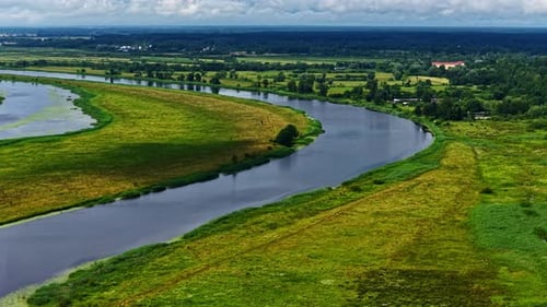 Picturesque drone shot of river passing through green fields over a vast green landscape during dayt