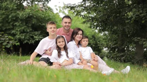 A Family is Sitting on the Grass in a Park