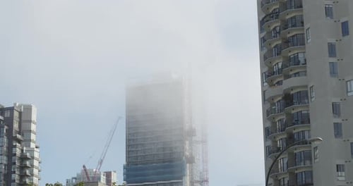 Contruction work on highrise timelapse with fog passing through.