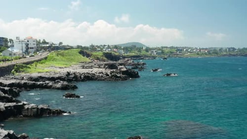 The clear sea, blue sky, and Jeju Island scenery with volcanic rocks.