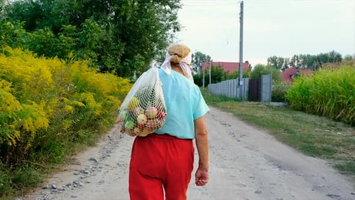 Woman Walking with Fruit on Rural Path