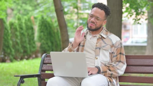 Man Works on Laptop in Park, Neck Pain
