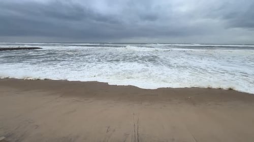 Des vagues de mer mousseuses entrent et se retirent, laissant des motifs d'écume.