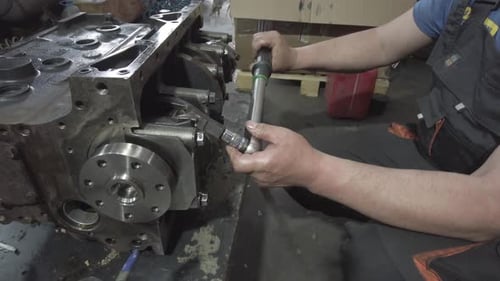 Mechanic Tightening Bolts on Large Engine with Wrench