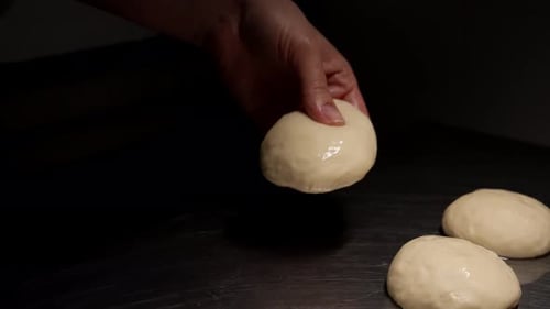 Hands Shaping Dough Portions on Stainless Steel Surface