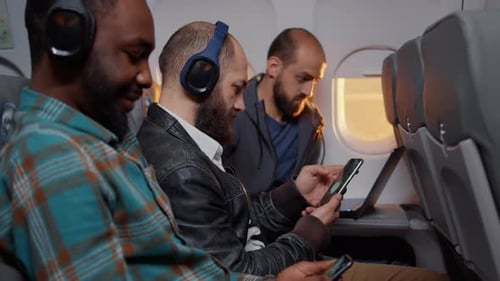 Adults Wearing Headphones Using Mobile Phones on Airplane