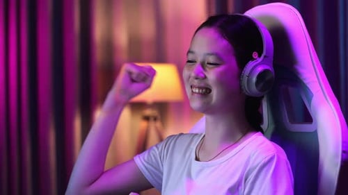 Close Up Of Excited Asian Teen Girl Gamer Celebrates Victory While Playing Video Game On Computer