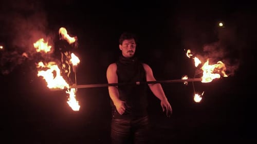Slowmotion, A Fire Artist Tricking With His Hands And His Fire Stick