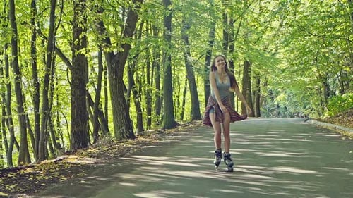 Woman Roller Skating Along Path in a Forest