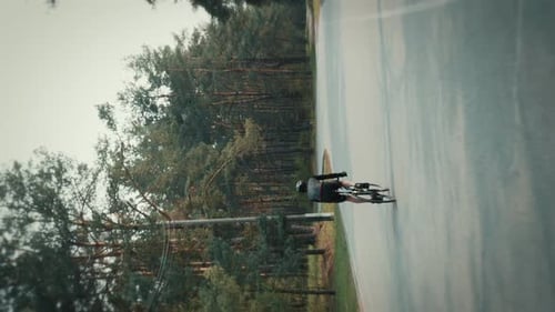 Cyclist Rides on a Road Through a Forest