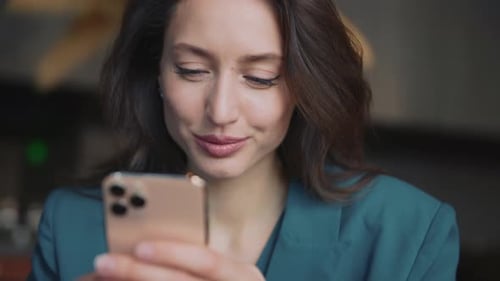 Woman Smiles While Using Smartphone Indoors