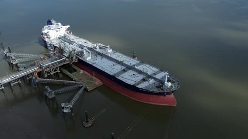 Crude oil tanker ship loading at refinery harbour terminal aerial view zoom in to deck