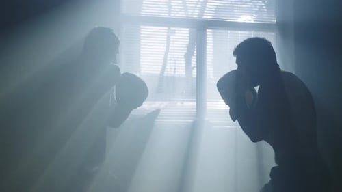 Silhouetted Men Boxing and Training Indoors