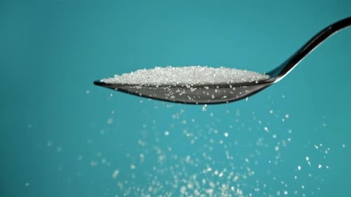 Sugar Pours Out of a Spoon on a Blue Background Filmed on a Highspeed Camera at 1000 Fps