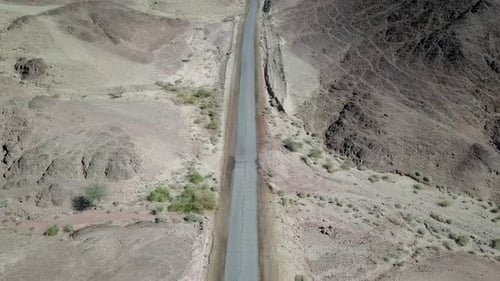 Empty desert road with mountains and blue sky in the background