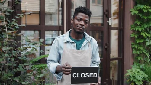 African American Cafe Worker Holding Signboard with Word Closed on It