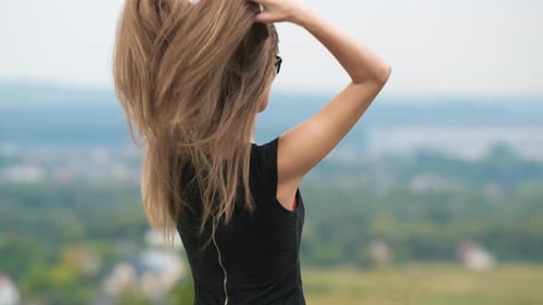 Woman Styles Hair in Ponytail Outdoors