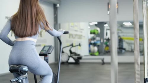 Cardio Workout of a Beautiful Longhaired Woman in the Gym on a Bicycle Exercise Bike