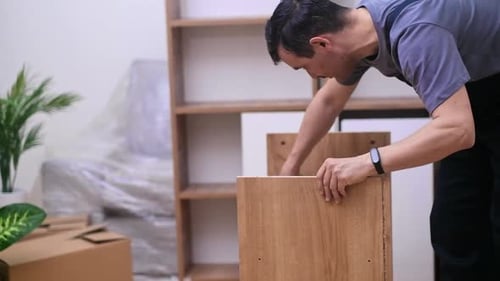 Man Assembling Wooden Cabinet in Bright Room