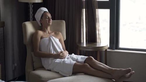Woman Relaxing in Chair After Shower in Hotel