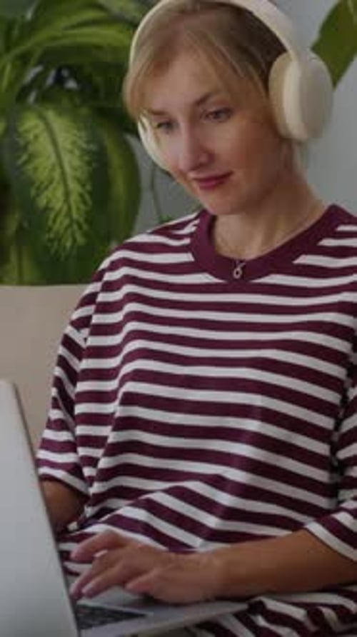 Woman with Headphones Using Laptop Inside Home