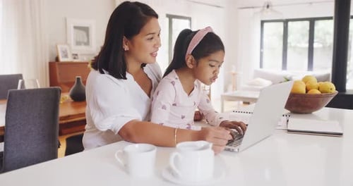 Woman Helping Child Use Laptop at Home