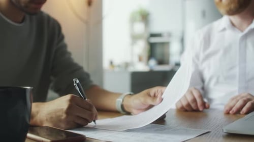 Adults Signing Agreement and Shaking Hands at Table
