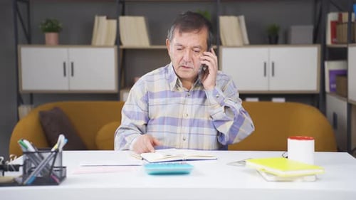 Man Taking Notes and Talking on Phone Indoors